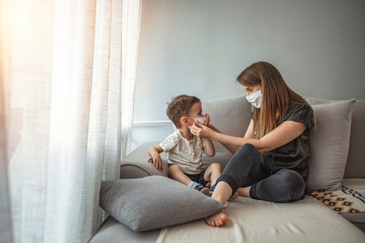 Mother helps a child with autism with wearing a face mask